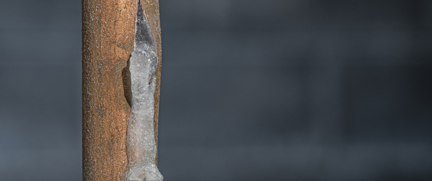 A close-up of a frozen copper pipe covered in frost. Conifer Colorado American Restoration water, flood and fire damage mitigation experts. Emergency services. Water damage clean up.